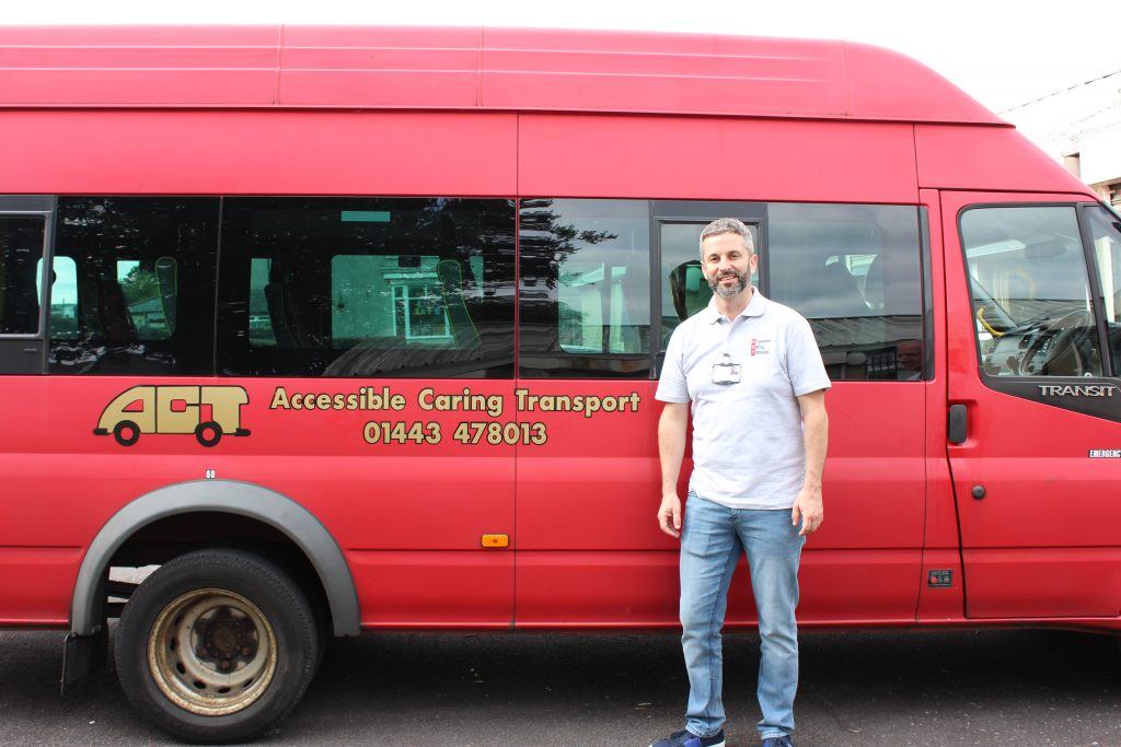 Trustee Greg Davies standing in front of an ACT bus